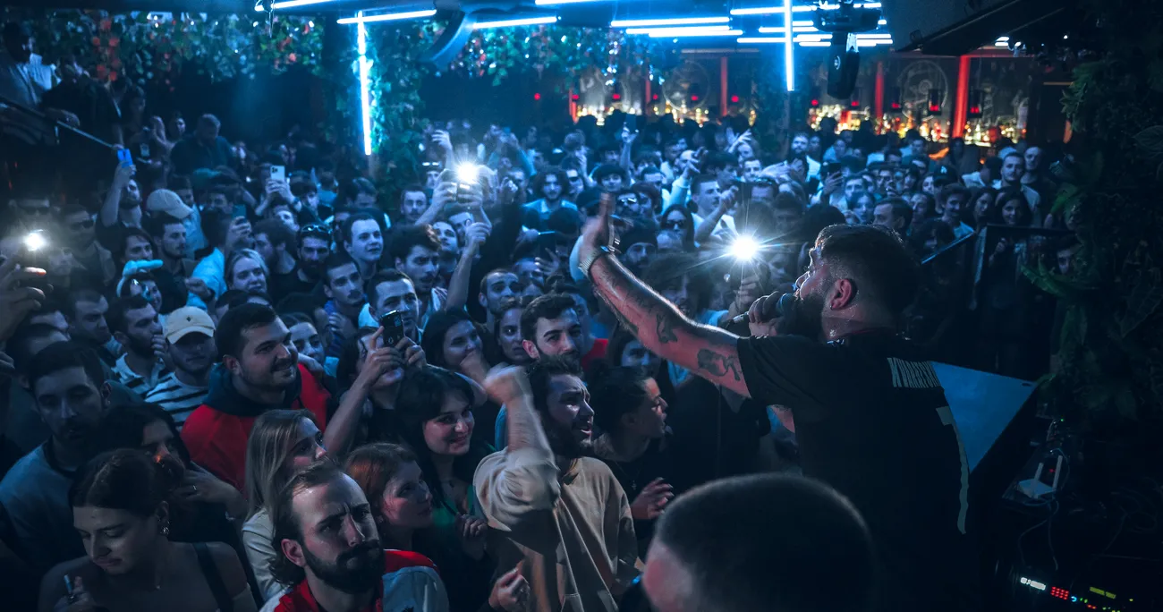 Packed peak-hour crowd under blue lights at Sakhelosno BAR Tbilisi